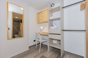 A bathroom with a mirror, a toilet, a chair, a shelf with towels, and a cabinet. - Edificio Bloom (Medellín)