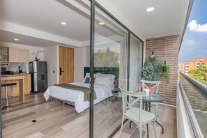 Een moderne hotelkamer met balkon, een kitchenette en een bed.