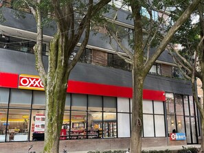 A building with a large glass storefront, a red awning, and a sign that reads 'Oxxo.' - Edificio Bloom (Medellín)