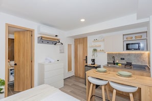 A modern kitchen with a wooden countertop, bar stools, and a microwave. - Edificio Bloom (Medellín)