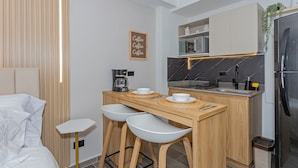 A modern kitchen with a wooden countertop, bar stools, a coffee machine, and a refrigerator. - Edificio Bloom (Medellín)