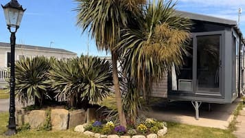 Un edificio moderno con fachada de vidrio, rodeado de un jardín bien cuidado con palmeras y plantas en flor.