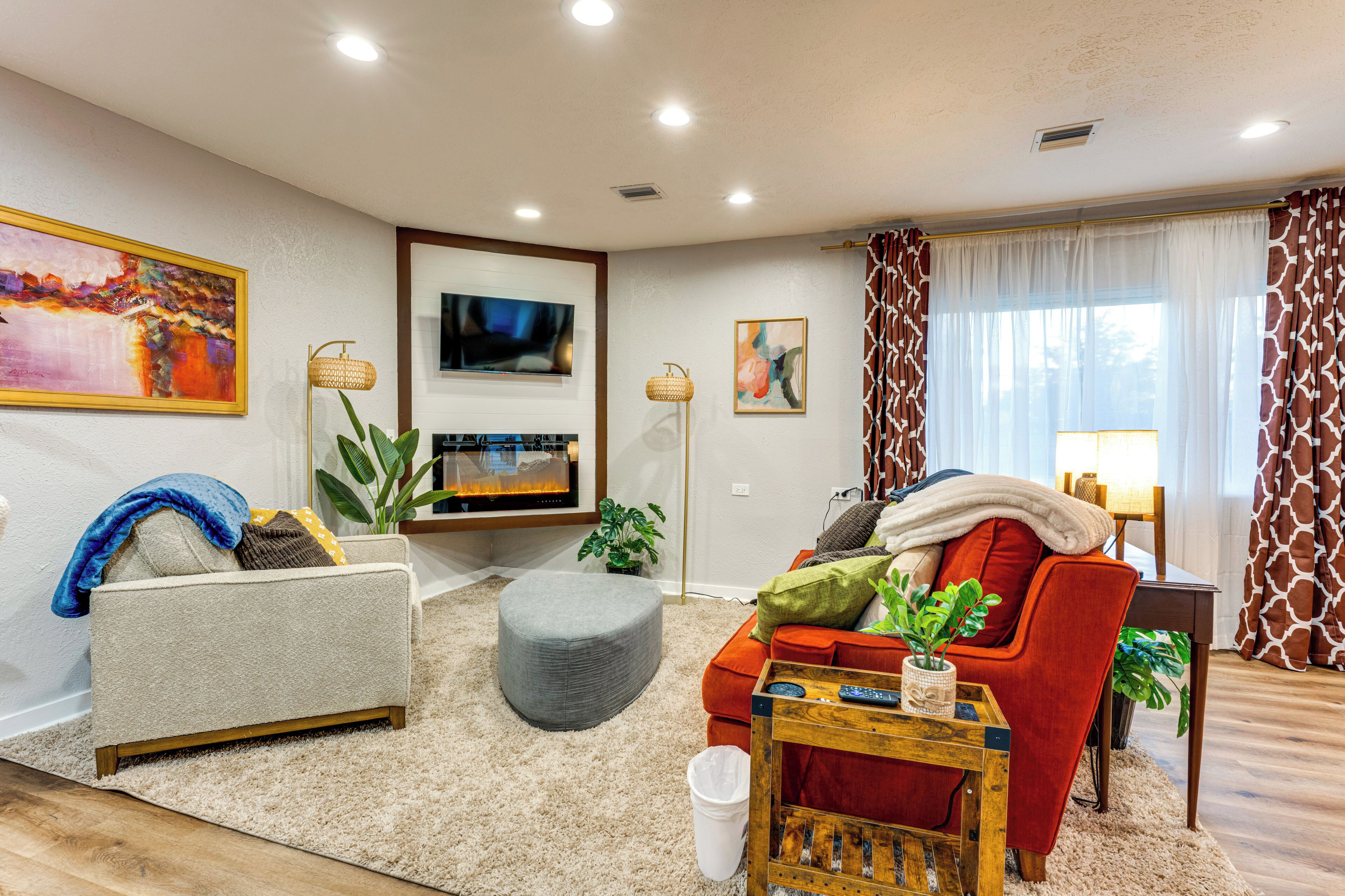 A living room with a sofa, ottoman, and a television.