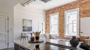 Een moderne keuken met een centraal eiland, een bakstenen muur en grote ramen.