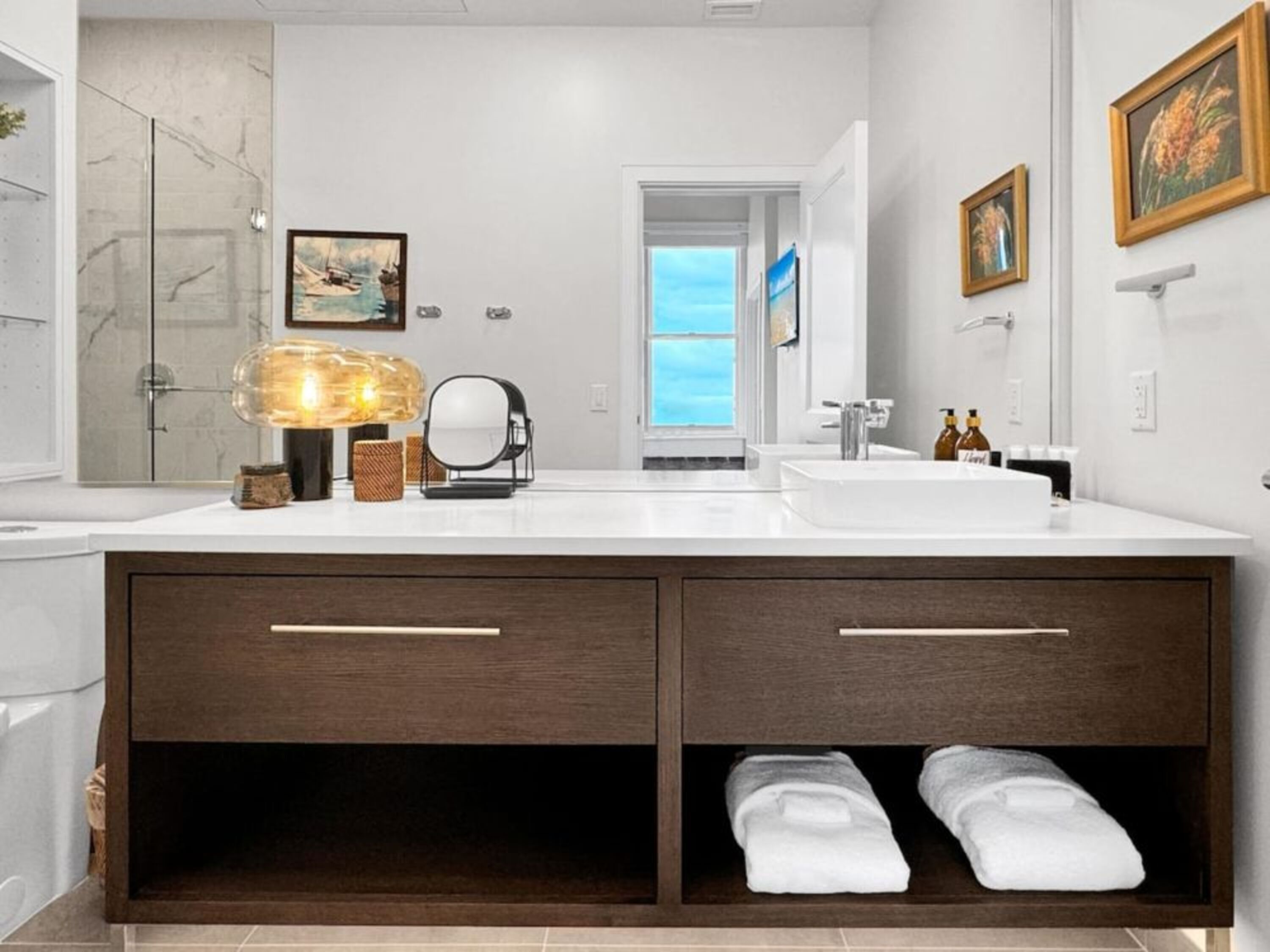 A modern bathroom with two sinks, a large mirror, and a towel rack.