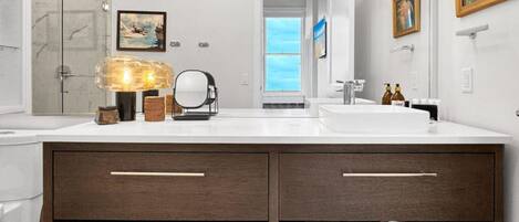 A modern bathroom with two sinks, a large mirror, and a towel rack.