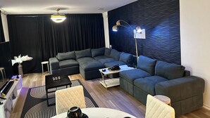 A modern living room with a sectional sofa, a coffee table, and a floor lamp. - Cozy Hideaway with Pool – Relax & Unwind Just Off the Highway (Maxwell)