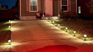 A two-story house with a front porch, a driveway, and a well-lit front yard. - Cozy Hideaway with Pool – Relax & Unwind Just Off the Highway (Maxwell)