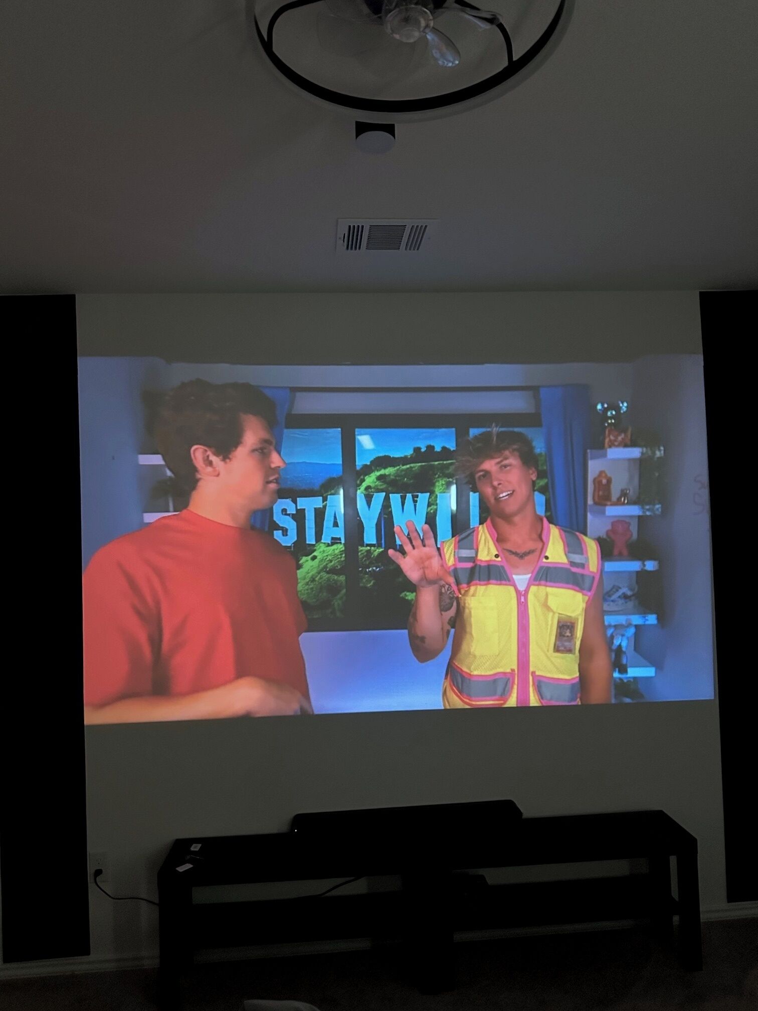 Una stanza con un grande schermo che mostra una scena di un film o programma televisivo.