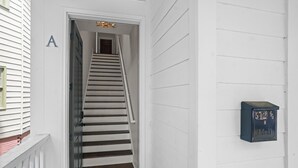 A white exterior with a wooden staircase leading to a door marked with the letter 'A'. A mailbox is attached to the wall. - The Peach House- Near Downtown (Savannah)