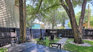 A backyard with a wooden table and chairs, surrounded by a wooden fence and trees. - The Peach House- Near Downtown (Savannah)