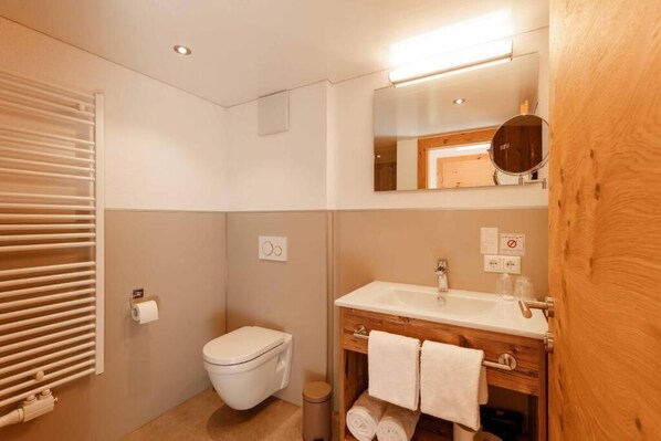 A bathroom with a toilet, a sink, and a mirror. - Landgasthof Adler (Hinterhornbach)