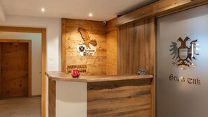 A reception desk with a wooden finish, a coat of arms, and a sign reading 'Gries Emk.' - Landgasthof Adler (Hinterhornbach)