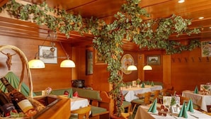 A restaurant with wooden walls, green foliage, and tables set for dining. - Landgasthof Adler (Hinterhornbach)