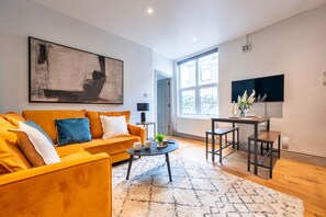 A modern living room with a sofa, coffee table, and a TV. - The Ground Floor Getaway (Cardiff)