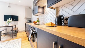 Eine moderne Küche mit einer Holzarbeitsplatte, einem eingebauten Ofen und einer Rückwand mit Fischgrätenmuster.