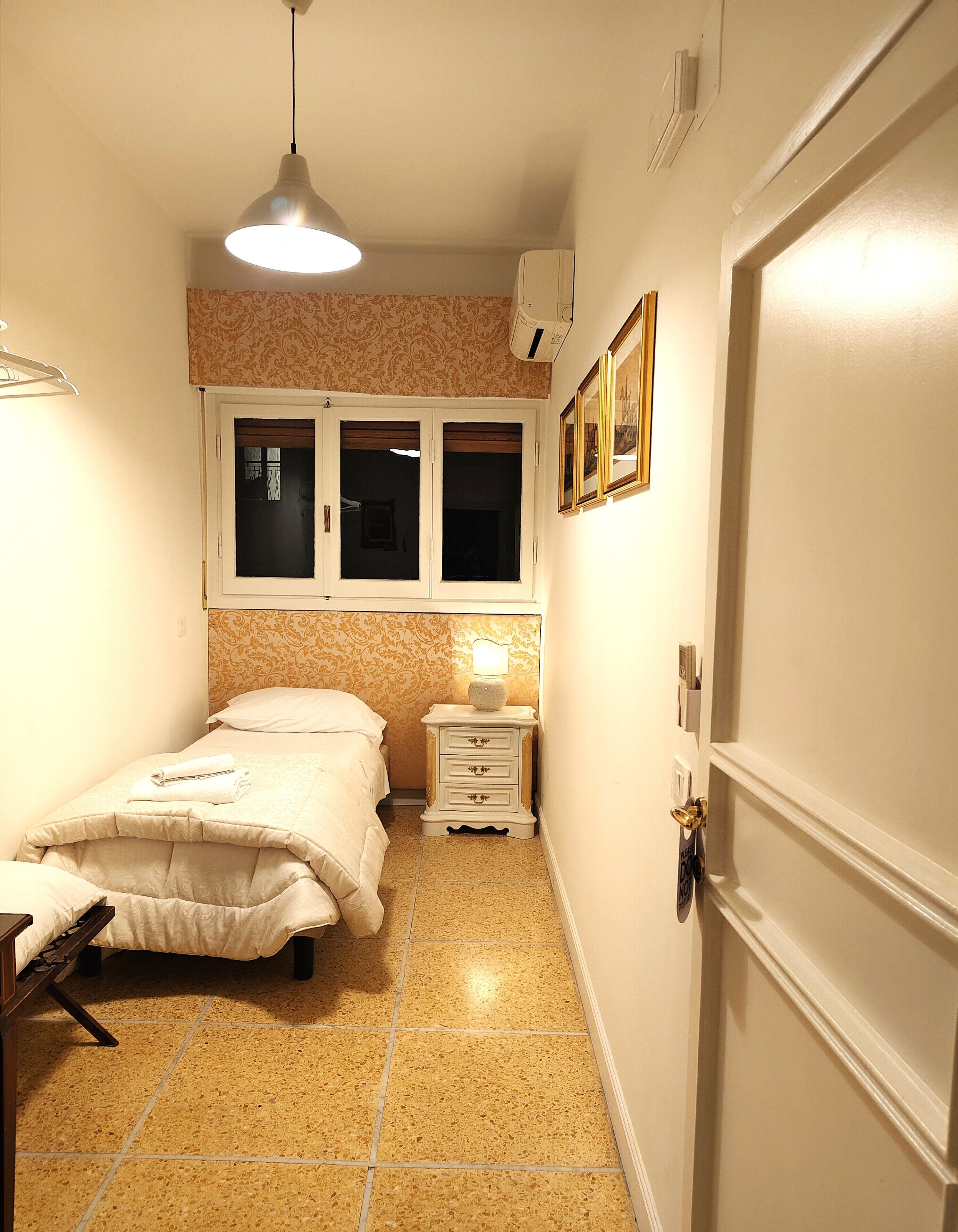 Una camera da letto con un letto, un comodino, una lampada e una finestra con tende.