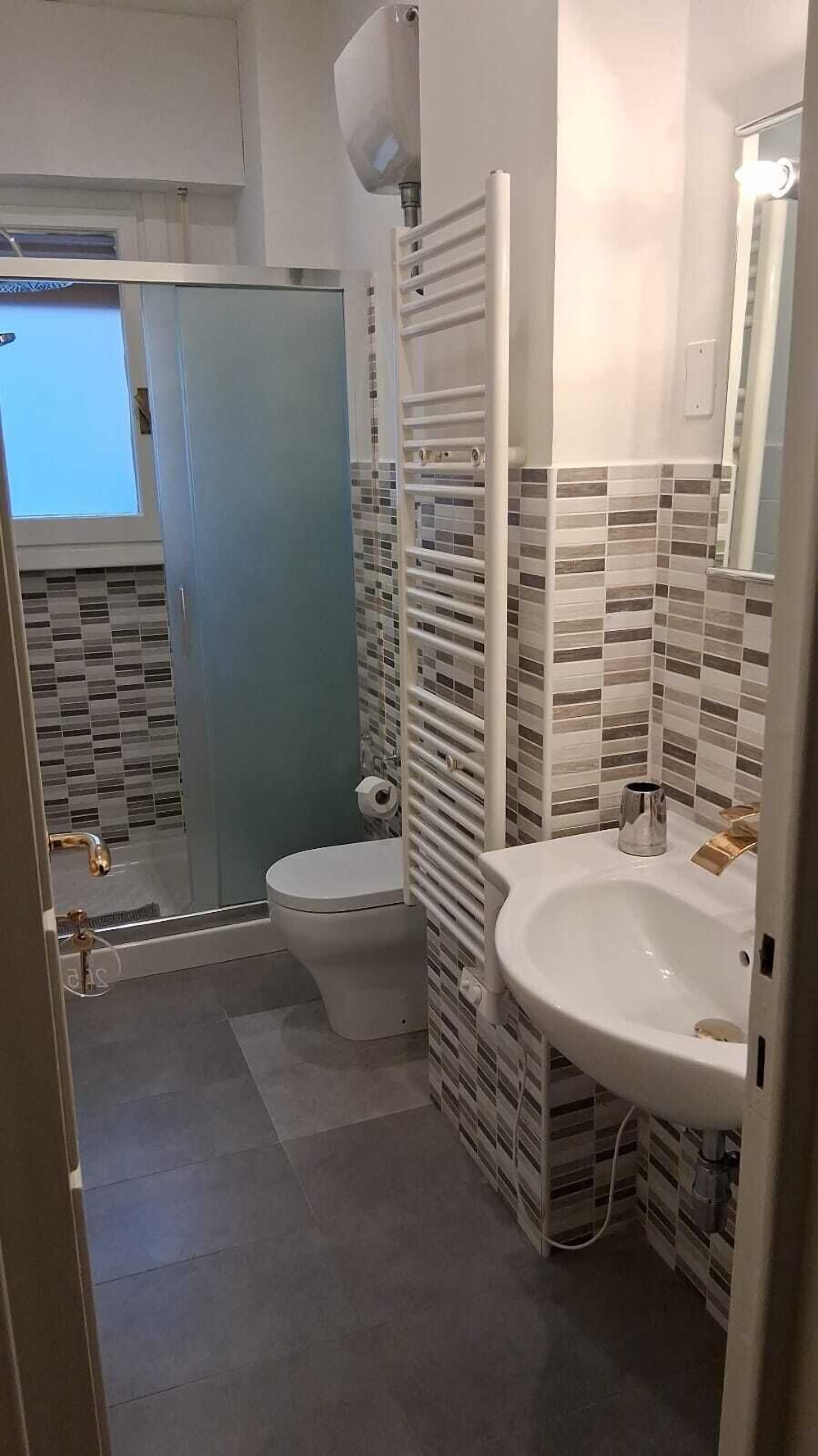 Ein Badezimmer mit Toilette, Waschbecken und Duschbereich.
