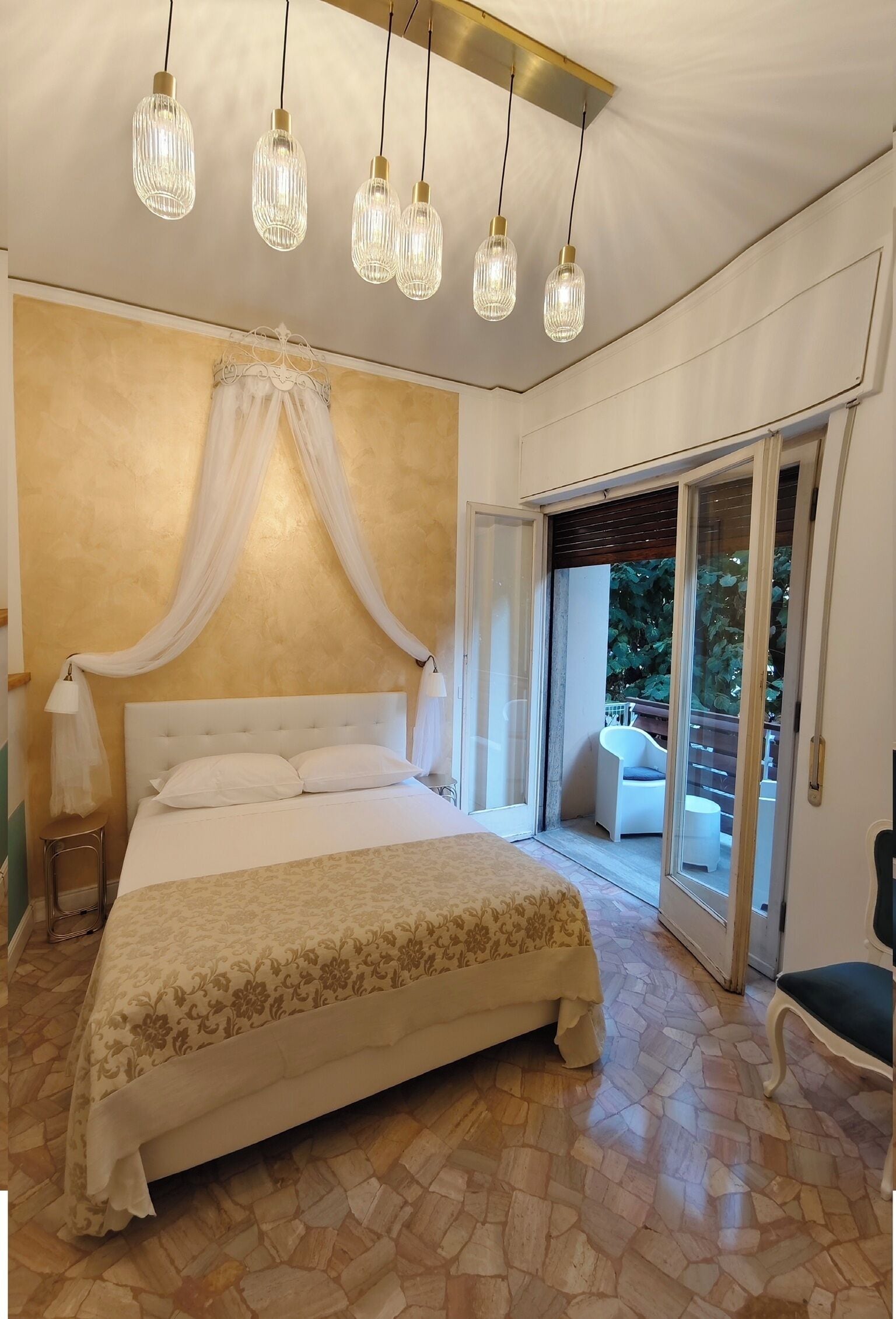 Un dormitorio con una cama grande, dosel y vista a un área exterior por una puerta corrediza de vidrio.