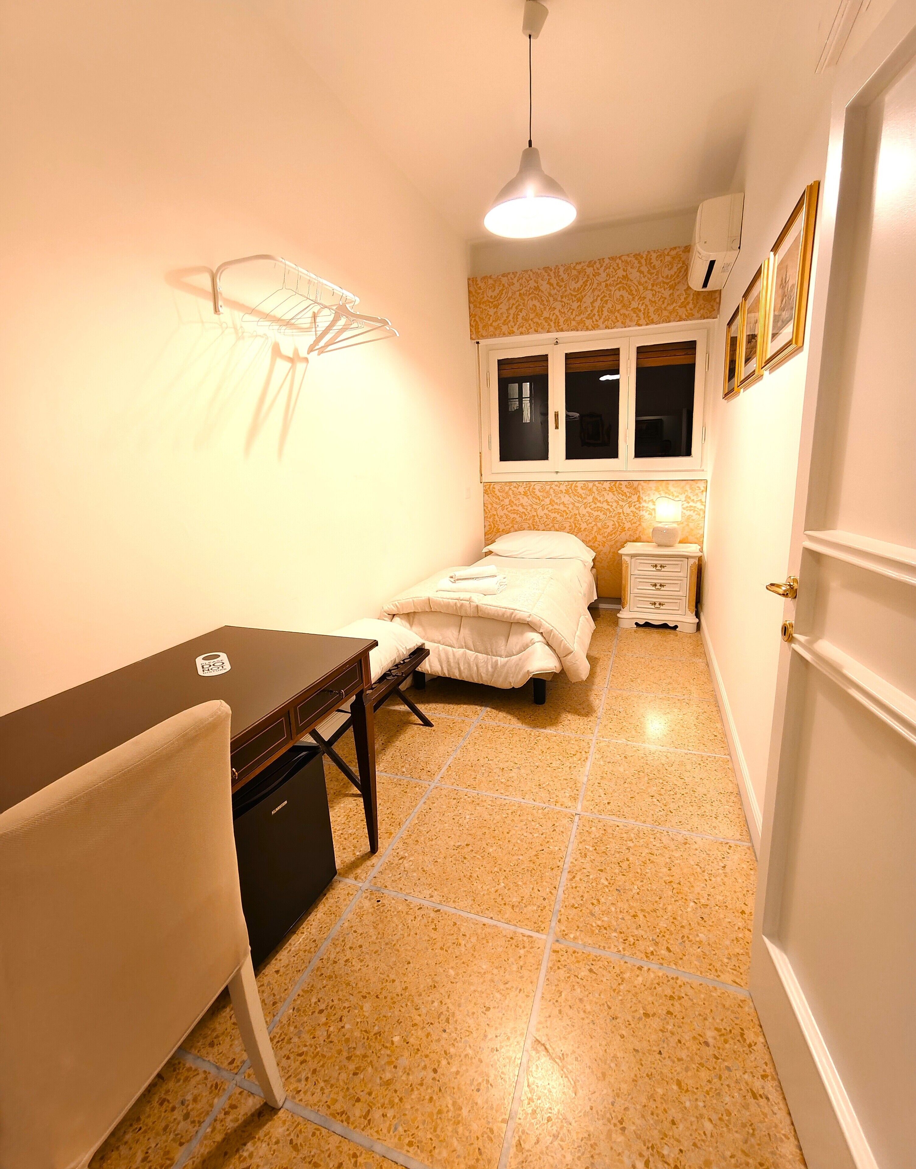 Une chambre à coucher de taille réduite, comprenant un lit, une table de chevet et un bureau avec une chaise.