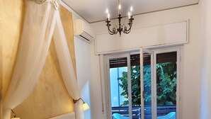 A bedroom with a large bed, a canopy, a chandelier, and a view of the outdoors. - B&B Cherubini 13 (Florence)