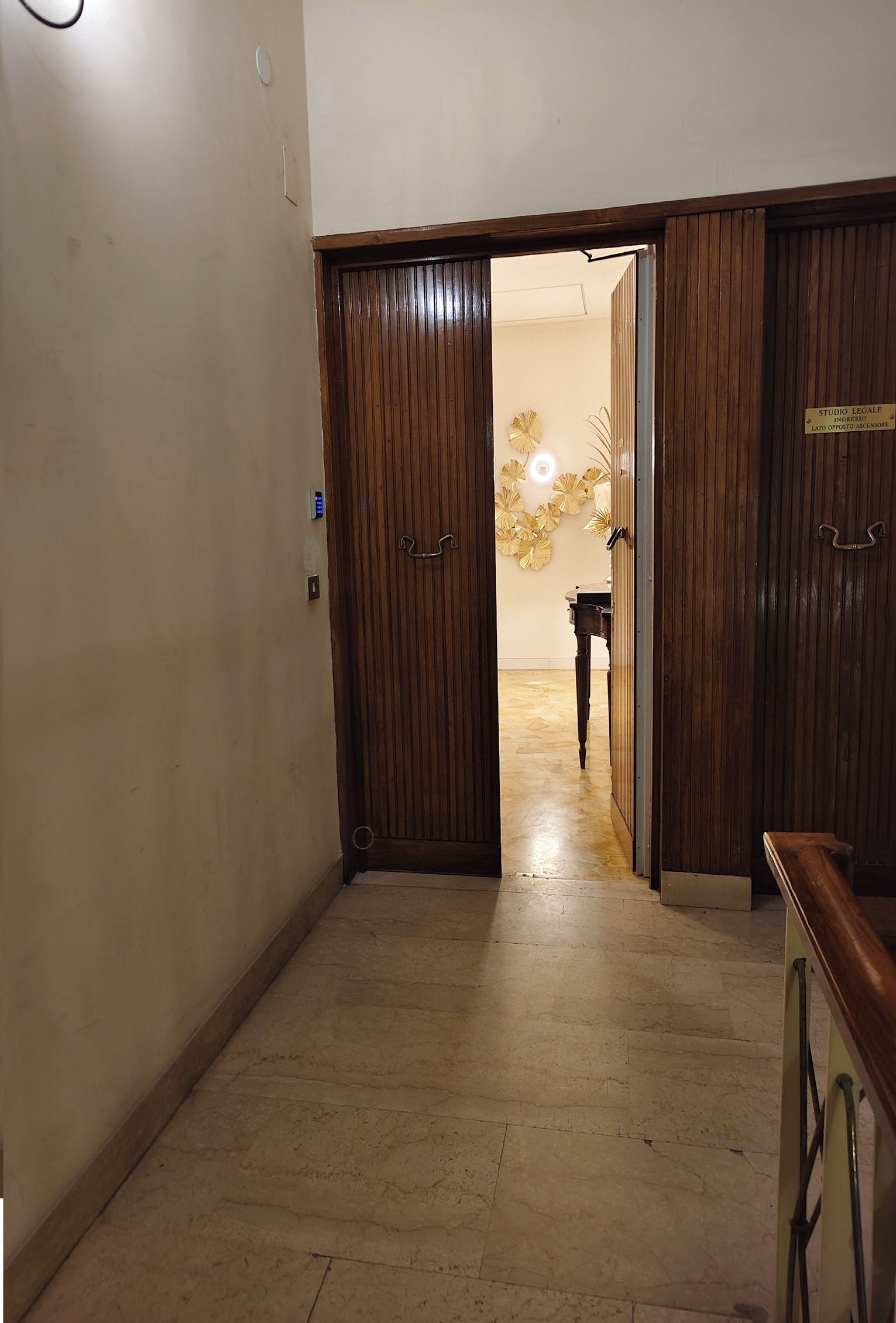 A hallway with wooden doors, a piano, and a decorative wall.