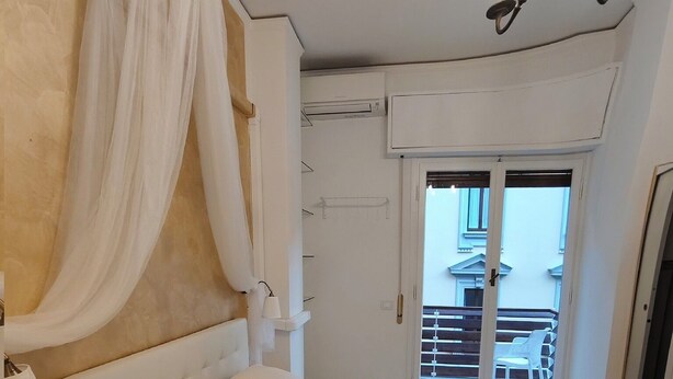 A bedroom with a large bed, a canopy, a chandelier, and a view of the outside balcony. - B&B Cherubini 13 (Florence)
