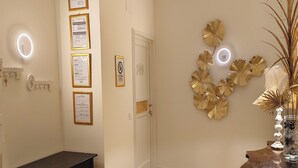 A hallway with a black table, framed certificates on the wall, a door with a number, and decorative gold leaf wall art. - B&B Cherubini 13 (Florence)