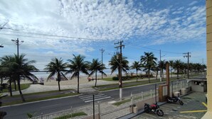 Uitzicht op het strand met palmbomen, een weg en een geparkeerde motor.