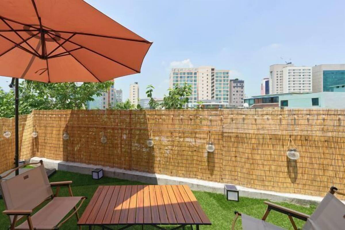An outdoor patio with a wooden table and chairs, a large umbrella, and a brick wall.