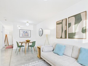 Ein modernes Wohnzimmer mit einer Couch, einem Esstisch mit Stühlen und einer Stehlampe.