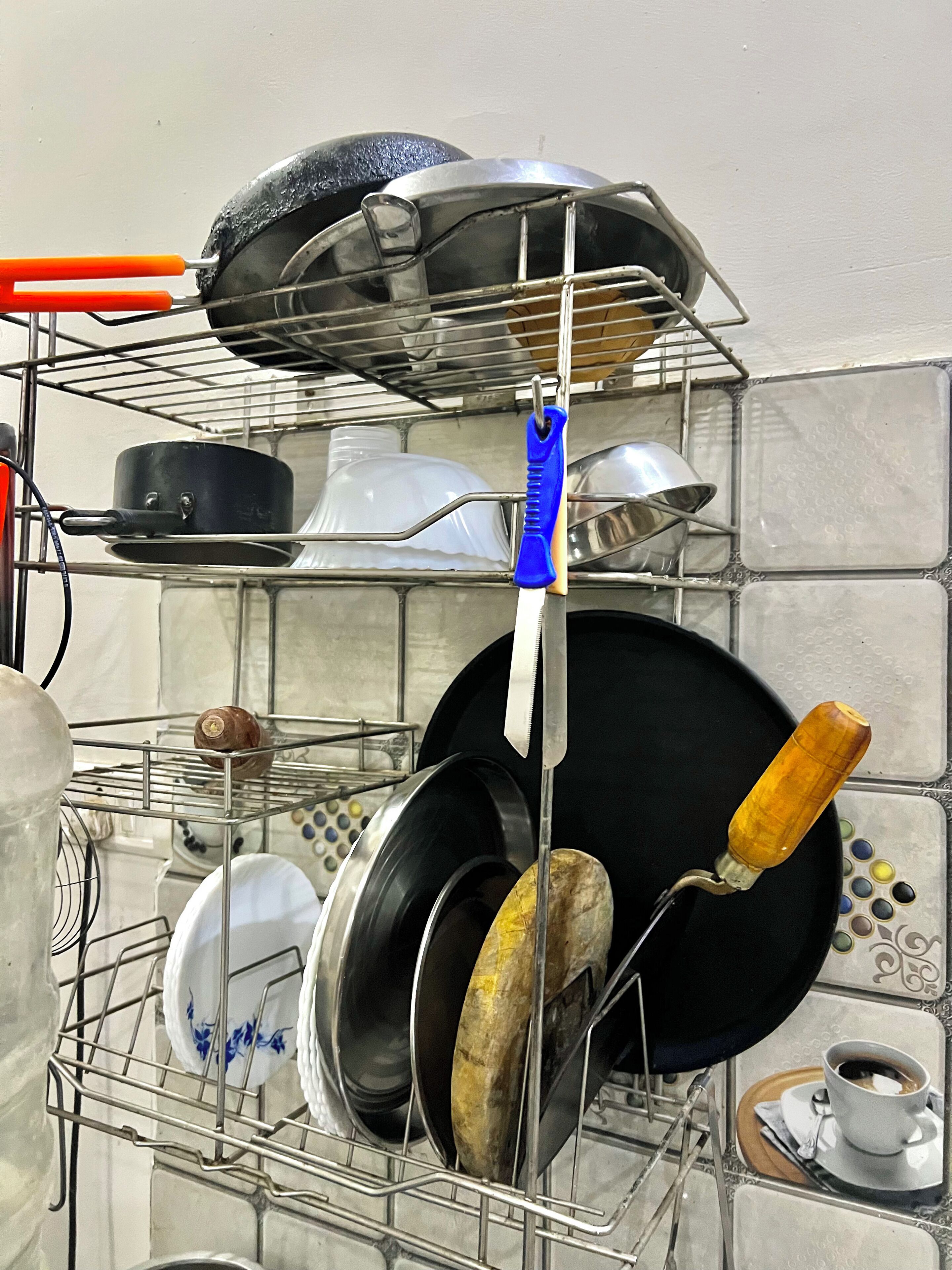 A kitchen with a metal rack holding various pots and pans.