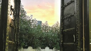 Un portail ouvert donne accès à une zone clôturée, avec un bâtiment visible au loin.