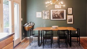 A dining area with a wooden table, black chairs, a chandelier, and framed pictures on the wall. - Charming three bedroom near Glacier National Park (Columbia Falls)