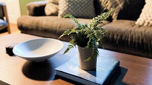 A cozy living room with a wooden coffee table, a bowl, a potted plant, and a book. - Charming three bedroom near Glacier National Park (Columbia Falls)