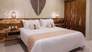 A neatly made bed with white linens and decorative pillows, a wooden headboard, bedside lamps, and a wooden wardrobe.
