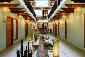 A corridor with wooden beams, hanging lights, and a central water feature with cacti. - Luuna de Jade (Oaxaca)