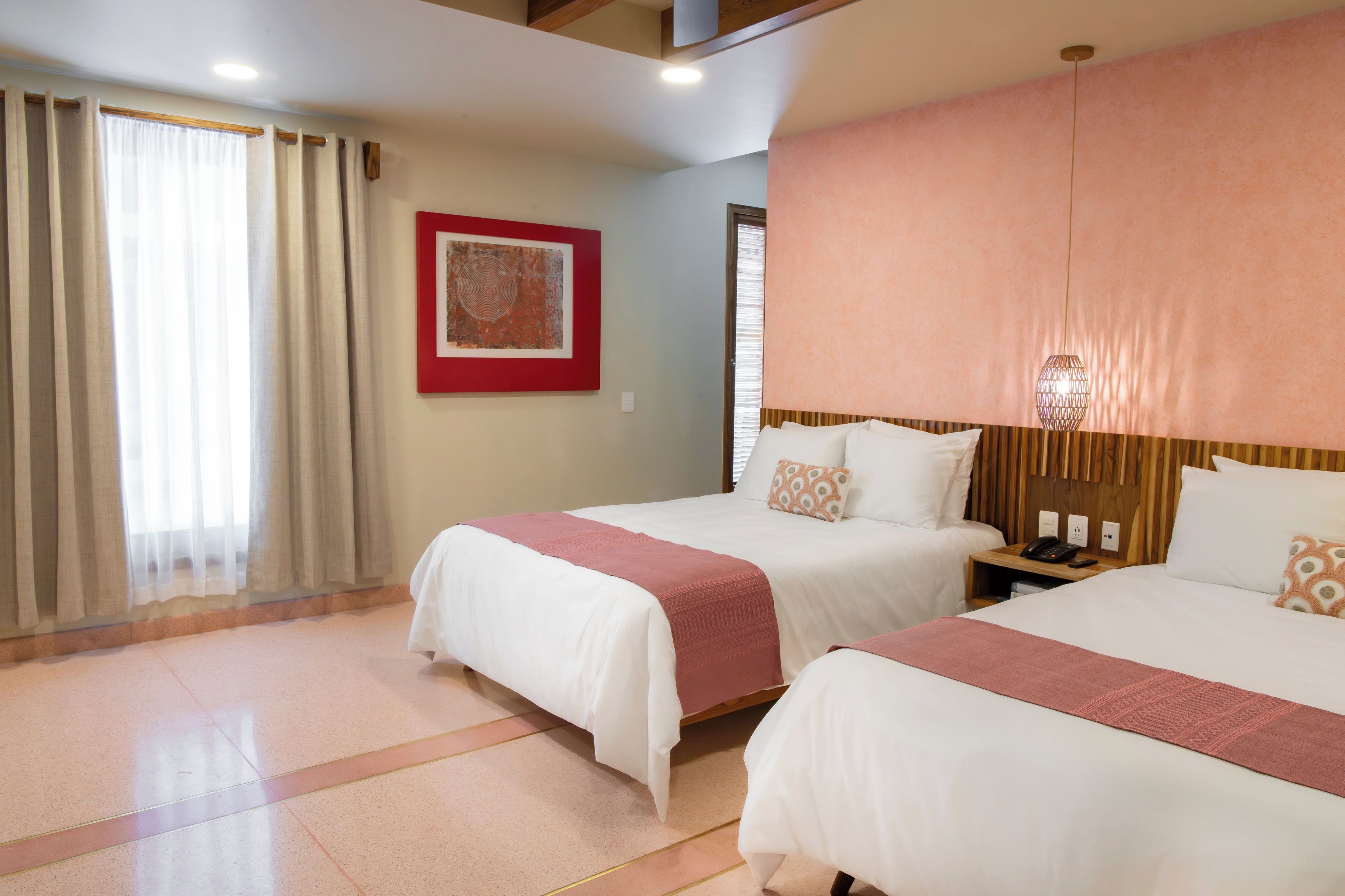 A hotel room with two beds, a nightstand, a telephone, and a framed picture on the wall.