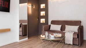A modern living room with a brown sofa, a glass coffee table, and a wall-mounted TV displaying the word "FLIX". - Lux&easy Athens Downtown Apartments (Athens)