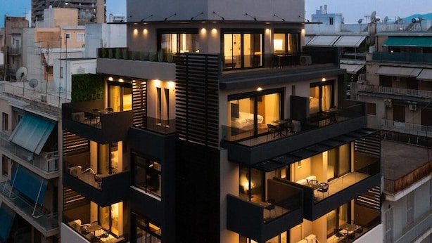 A multi-story building with balconies, large windows, and a central tower with a logo. - Lux&easy Athens Downtown Apartments (Athens)