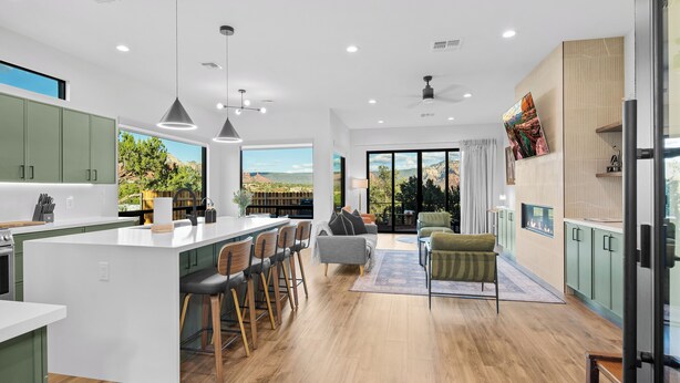 A modern kitchen with a large island, bar stools, and a view of a mountainous landscape.