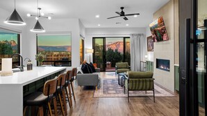 A modern kitchen with a bar area, seating, and a large window with a mountain view.