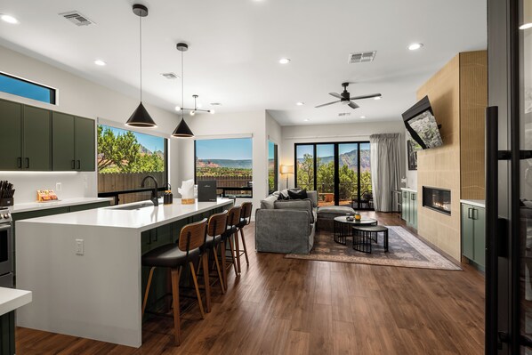 A modern kitchen with a central island, bar stools, and a dining area with a view of the mountains.