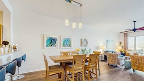 A modern living room with a wooden dining table, matching chairs, and a sofa. - Dog friendly bayfront 4th floor condo with bay views heated pool and spa WD (Clearwater)