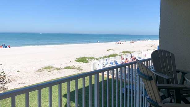 Blick auf den Strand von einem Balkon mit Geländer, Liegestühlen und Sonnenschirmen.
