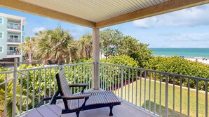 Ein Balkon mit Blick auf Strand und Meer, inklusive Tisch und Stuhl.