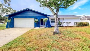 A two-story house with a blue exterior and a white garage door. - Bright and open home with private pool screened lanai enclosed yard and WD (Dunedin)