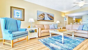 A living room with a striped armchair, a beige sofa, a coffee table, and a blue rug.