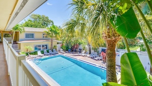 A swimming pool with lounge chairs and palm trees. - Beachside St Pete Condo w Heated Pool Near Landmark Restaurants (St. Pete Beach)