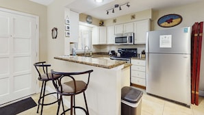 A compact kitchen with a central island, a microwave, a refrigerator, and a sink. - Beachside St Pete Condo w Heated Pool Near Landmark Restaurants (St. Pete Beach)